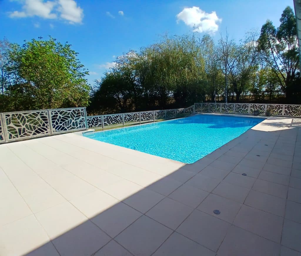 Garde-corps en inox 316 L pour sécuriser une piscine et clôturer sa terrasse. Garde-corps garni d'un motif central de feuilles. Motif découpé au laser. Ainsi, le motif allège l'ensemble de l'ouvrage permettant de l'intégrer plus facilement dans l'espace de verdure environnant, tout en étant fonctionnel.
