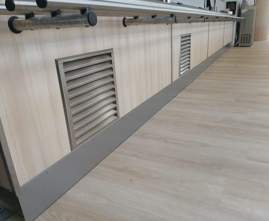 Réalisation et installation d'une plinthe, sur mesure, en inox pour le bas d'un meuble de service des repas d'une cafétéria. Photo après.