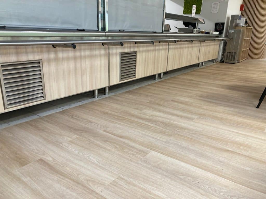 Réalisation et installation d'une plinthe, sur mesure, en inox pour le bas d'un meuble de service des repas d'une cafétéria. Photo avant.